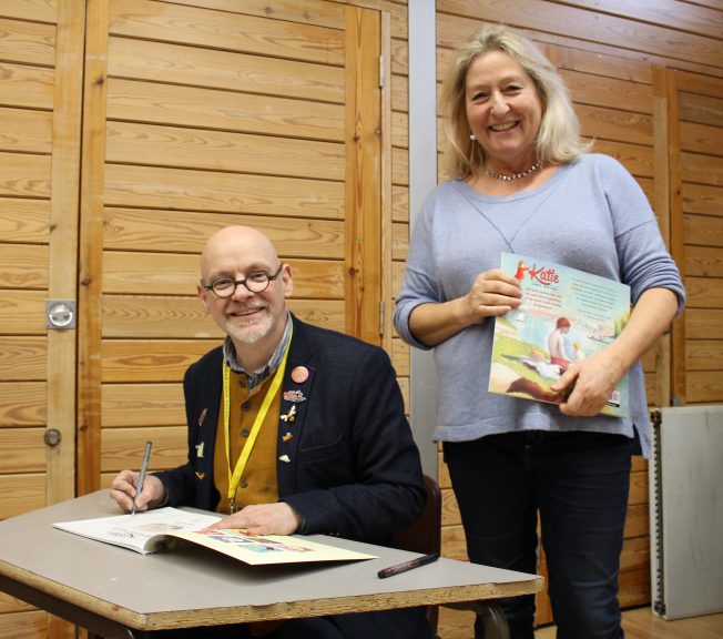 Two members of staff holding and writing in a picture book