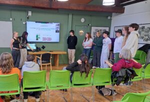 Sixth Form students from The King Alfred School stand at the front of a classroom presenting to Harvard researchers via a big screen