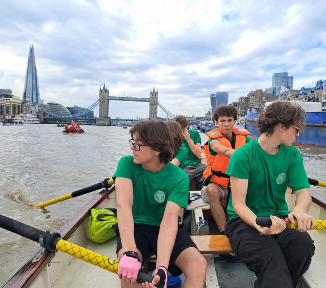 Students from The King Alfred School Sixth Form rowing a boat on the RIver Thames, with the Shard and London Bridge in the background