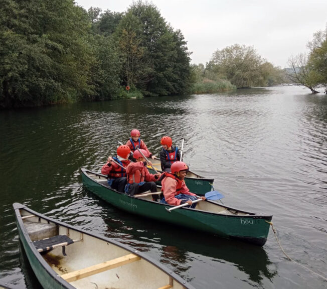 Students from The King Alfred School in a green canoe boat on a lake