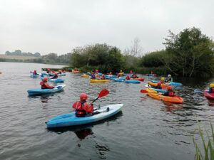 Students from The King Alfred School in blue and orange kayaks on a lake