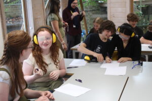 Sixth Form students from The King Alfred School sit around tables wearing goggles and headphones as part of dementia training