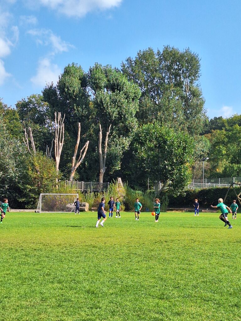 The football pitch at The King Alfred School, with players in green and black kits pictured mid-game