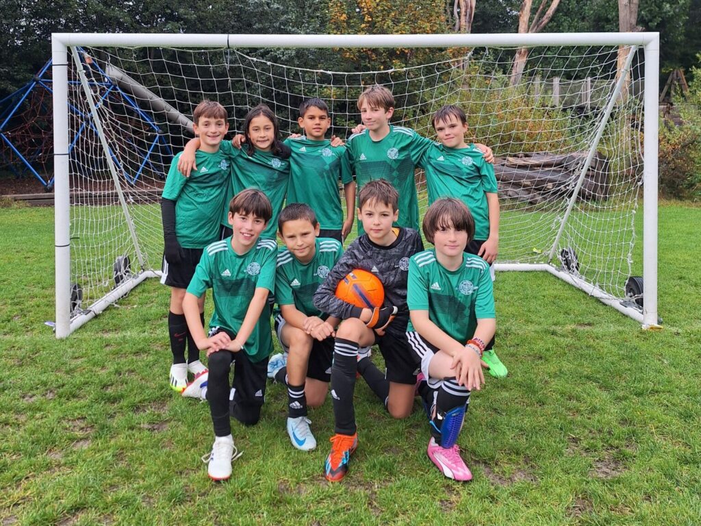 Boys from The King Alfred School dressed in green football kit, standing in front of a goal.