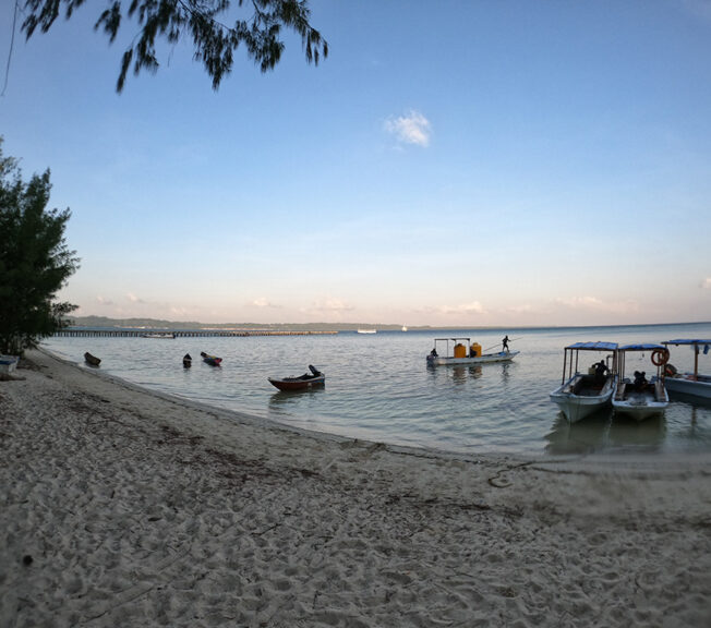 An Indonesian beach at dusk, with boats in the water