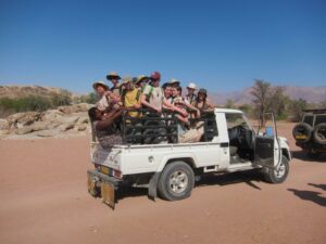 Students from The King Alfred School stand in the back of a white truck in the Namibian desert