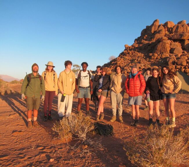 Students from The King Alfred School stand in a line in the Namibian desert at sunset