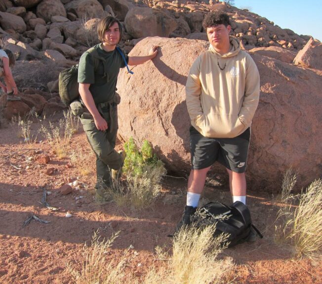 Two students from The King Alfred School stand next to a large rock in the Namibian desert