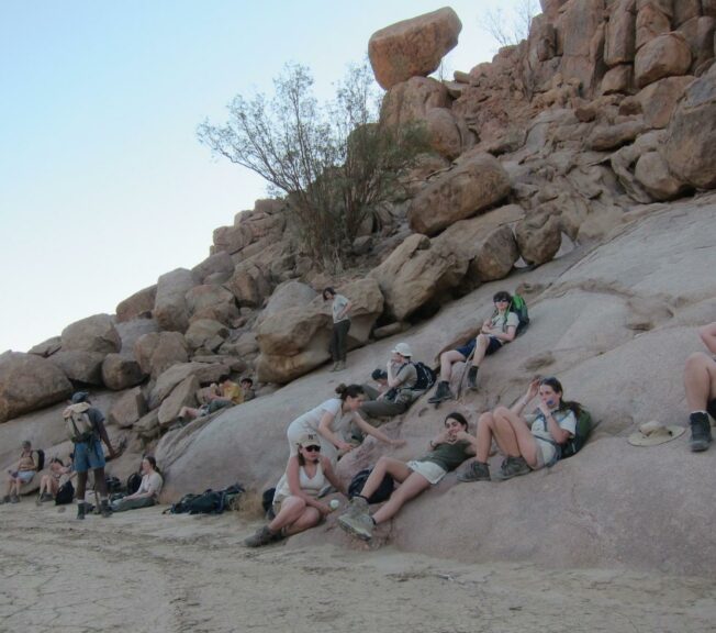 Students from The King Alfred School lie on a shady hillside in the Namibia desert