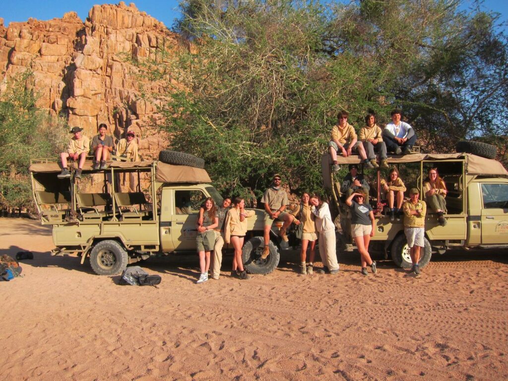 Students from The King Alfred School pictured in front of two trucks, some sitting on the roof and some standing