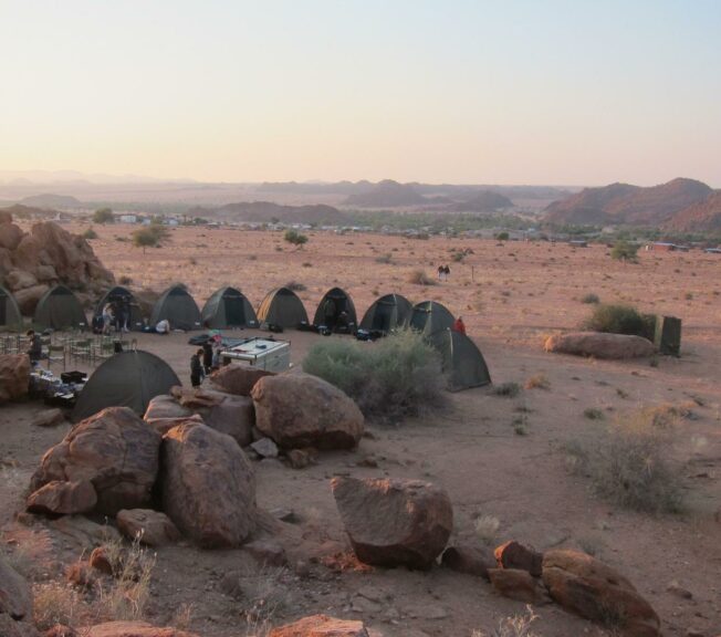 Wide shot of the Namibian desert landscape, with a ring of tents