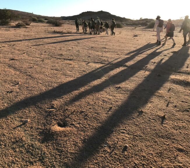 Students from The King Alfred School trek across the Namibian desert, throwing long shadows on the ground