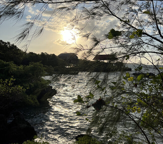 Indonesian coastline in shadow as the sun sets behind clouds