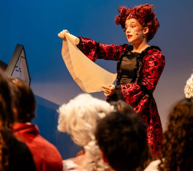 Female actor reads from a script on stage