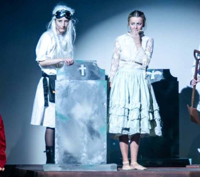 Actors around a gravestone on stage