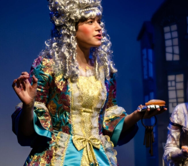 Actor wearing an elaborate Regency wig on stage