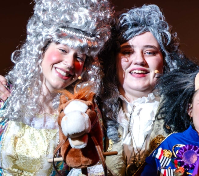 Close-up of three smiling actors in Regency outfits