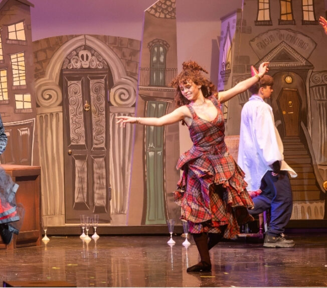 Three female performers dance on stage