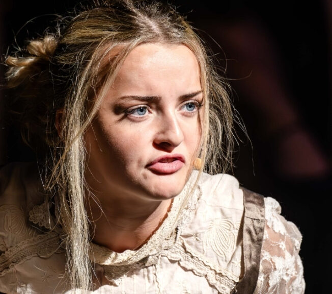 Close-up of a blonde girl singing, her face full of emotion