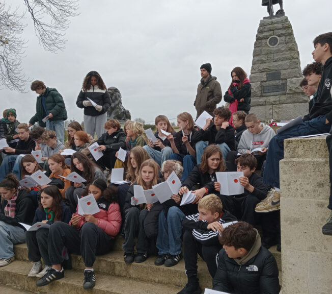 Students listening to poetry in front of a WW1 memorial