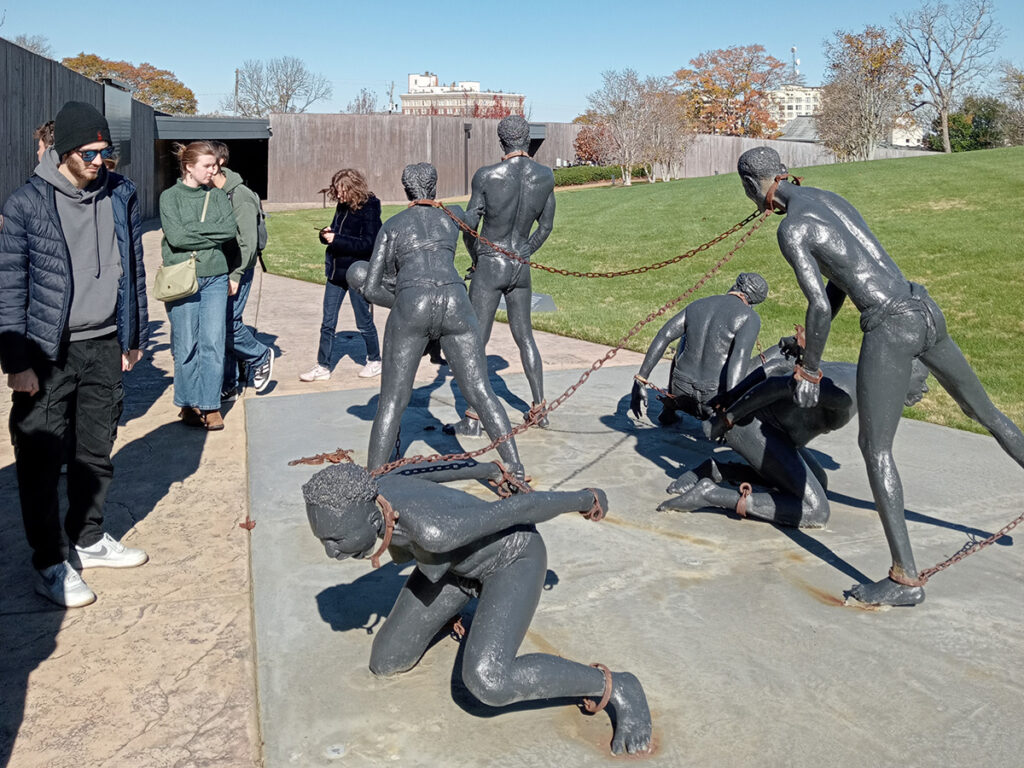 Students look at sculptures depicting African American slaves in chains at The National Memorial for Peace and Justice in Montgomery, Alabama