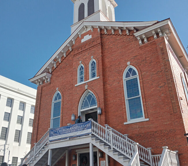 Exterior of Dexter Avenue King Memorial Baptist Church, a red brick building set against a blue sky