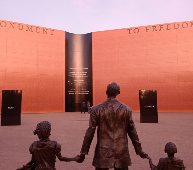 Statues of an African American man holding hands with two children in front of The National Monument to Freedom