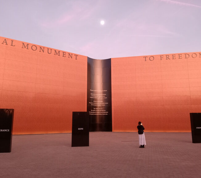 A lone student stands in front of The National Monument to Freedom, a terracotta wall inscribed with the names of more than a hundred and twenty thousand former slaves