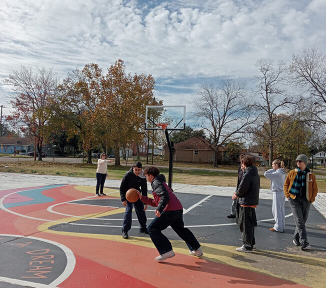 Students play basketball on a multicolours court, with the words 'I have a dream' in the centre circle