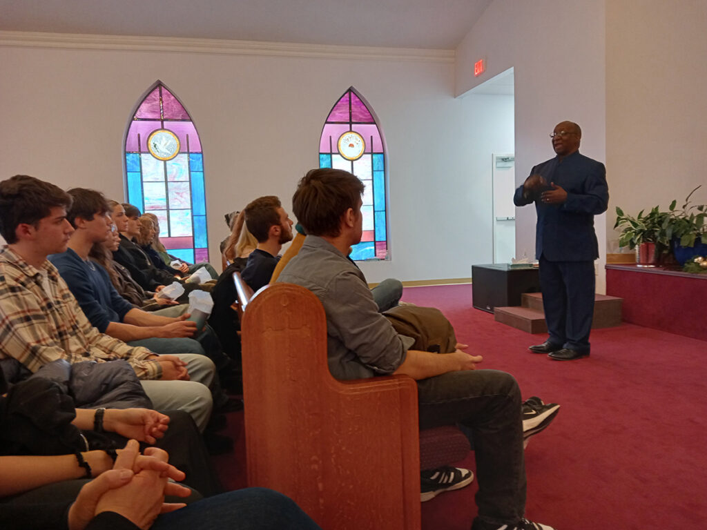 Students sit in the pews of the Mount Zion African Baptist Church as they listen to pastor Dr Alvin Edwards talk