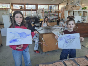 Year 7 students hold up some of the artworks they've created