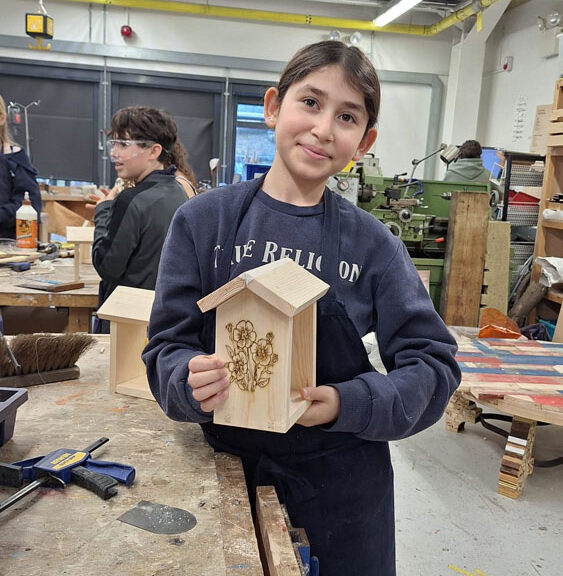 A student holds up a finished bird feeder